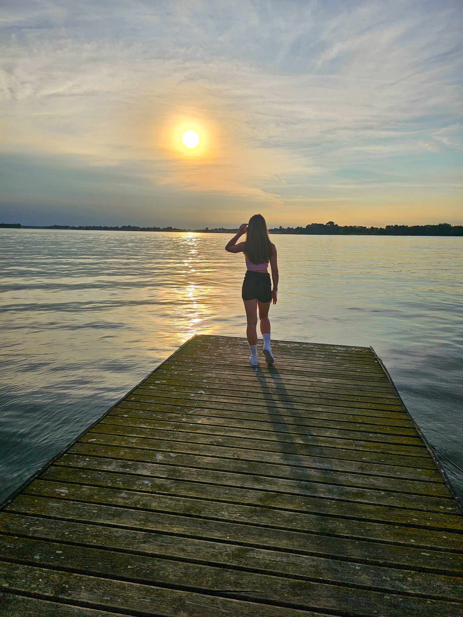 Osoba stojąca na pomoście, podziwiająca zachód słońca nad Zalewem Nielisz.